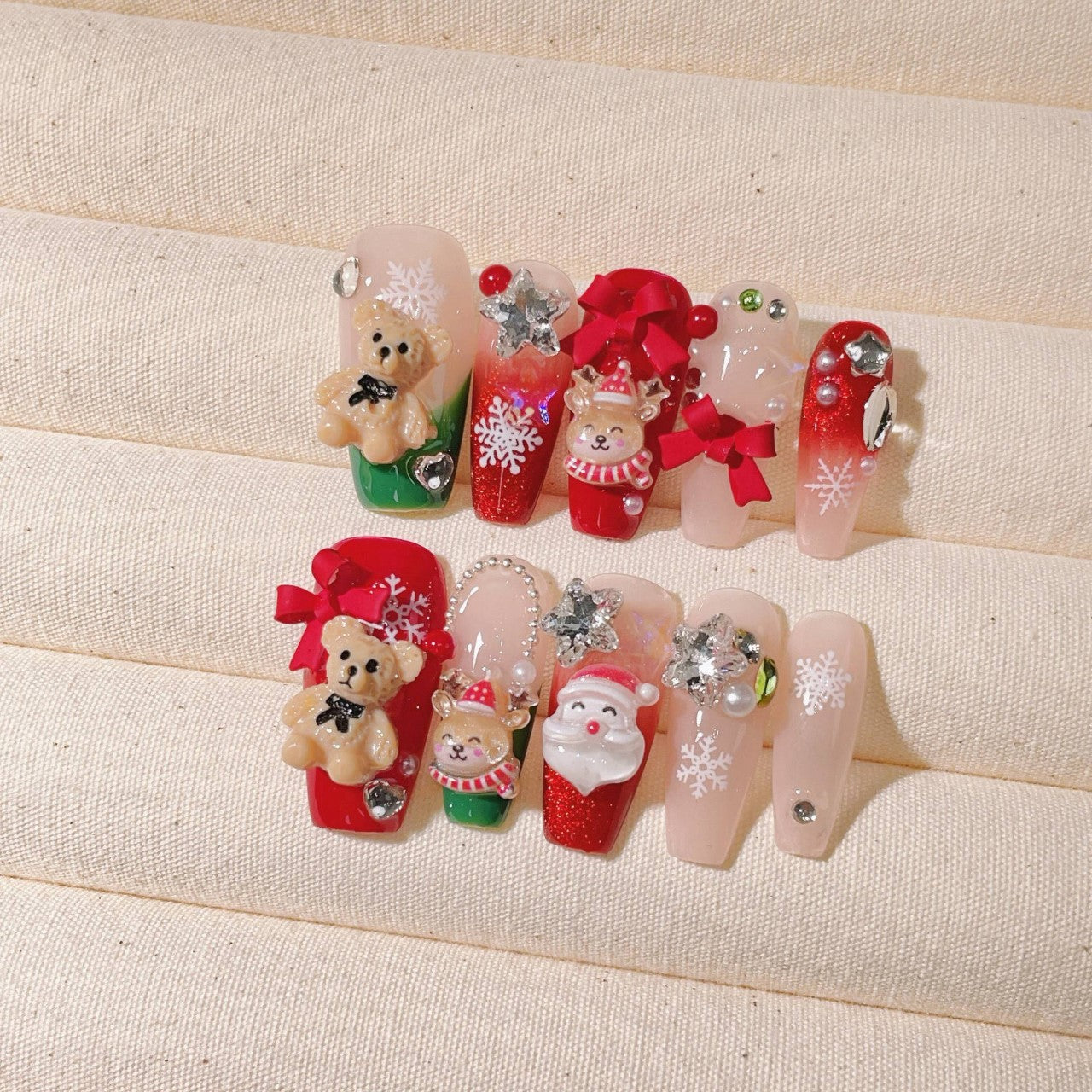 Festive Christmas-themed nails featuring detailed 3D designs, including Santa Claus, bows, snowflakes, and holiday ornaments, in red, white, and silver colors, creating a joyful and celebratory look.