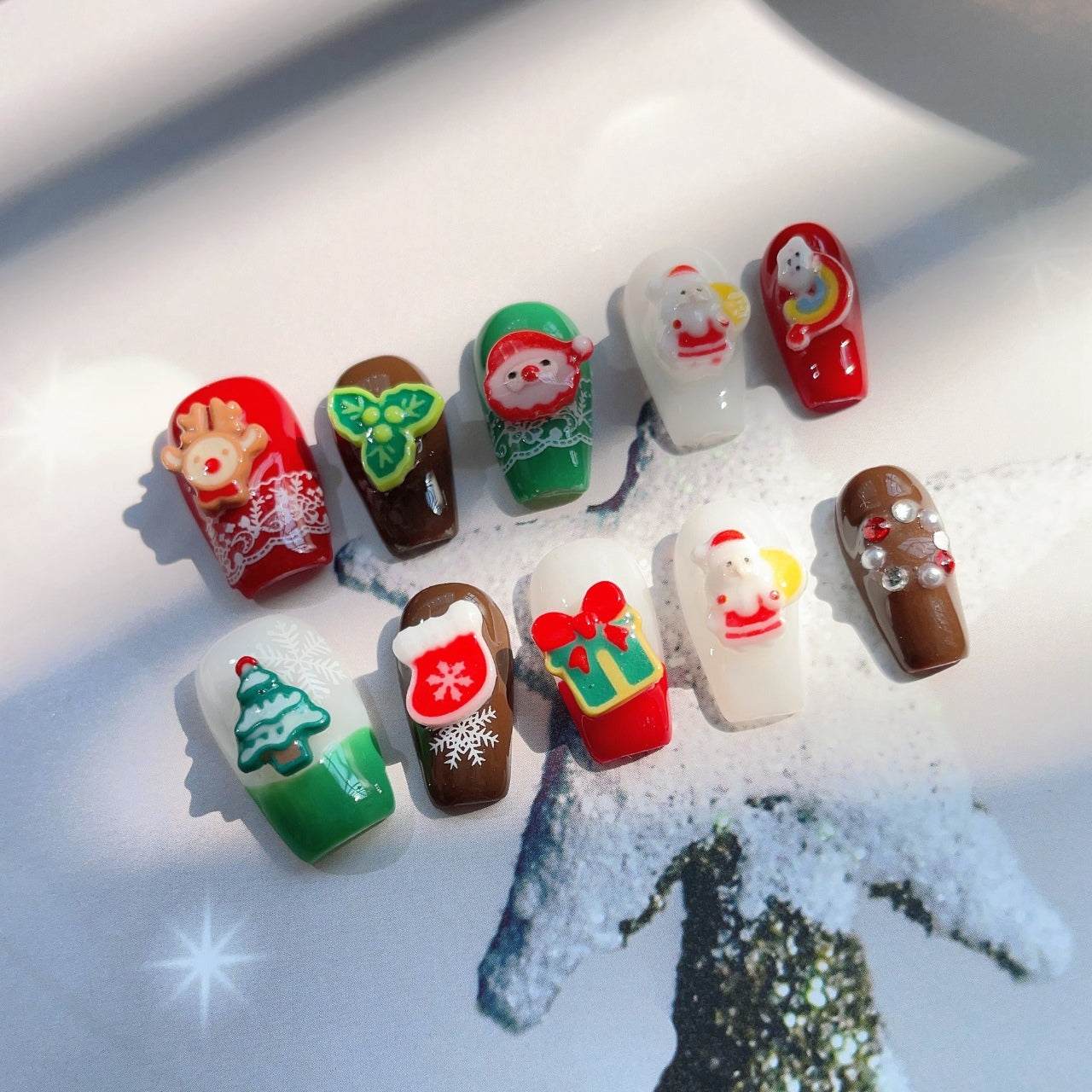 Festive Christmas-themed nails featuring detailed 3D designs, including Santa Claus, bows, snowflakes, and holiday ornaments, in red, white, brown and green colors, creating a joyful and celebratory look.