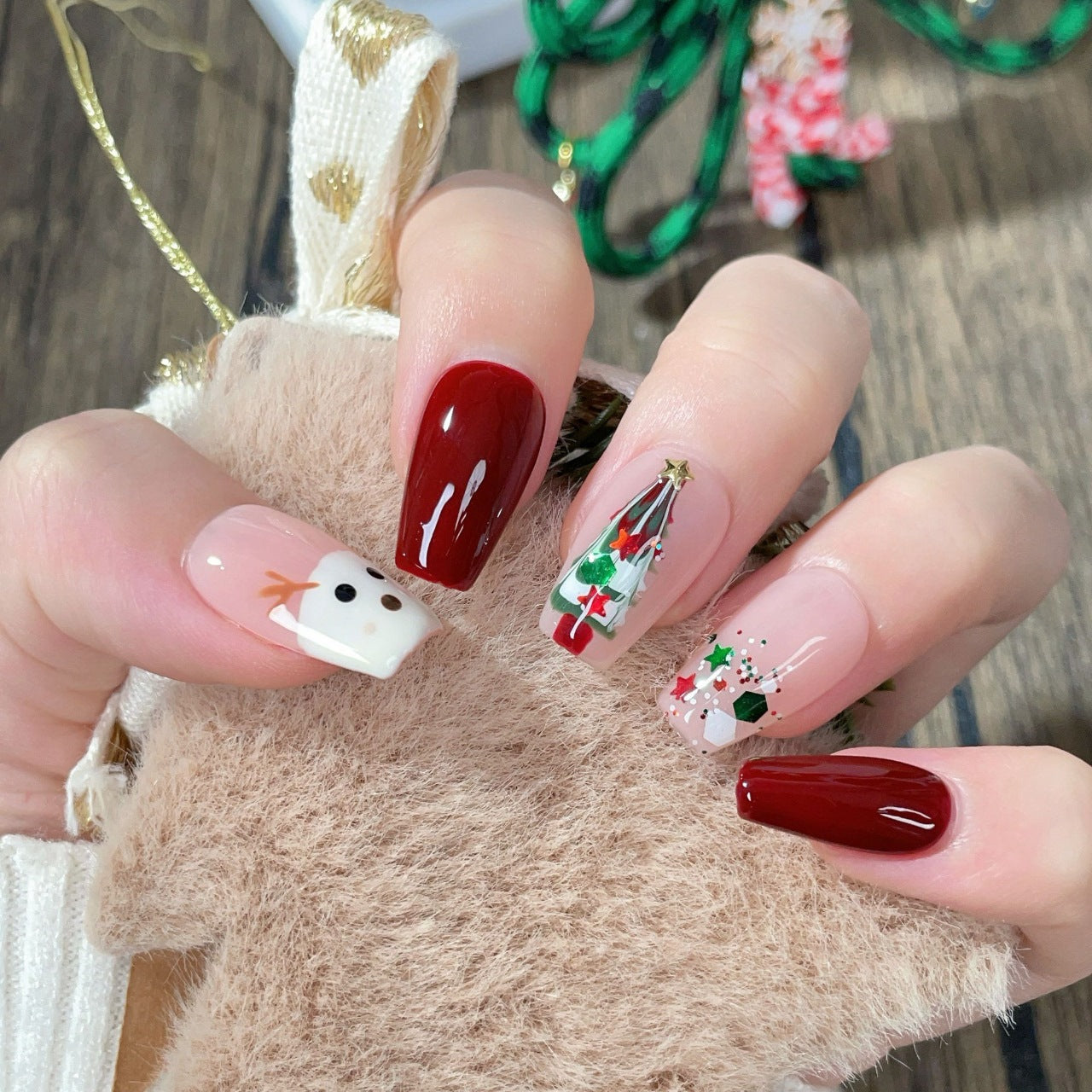 “Press-on nails featuring a charming Christmas theme with a detailed design of a deer and a Christmas tree. The deer is elegantly drawn,  adorned with ornaments and lights. The nails have a festive color palette, typically including red, green, and white, with a glossy finish, creating a holiday-inspired, whimsical, and cozy look.”