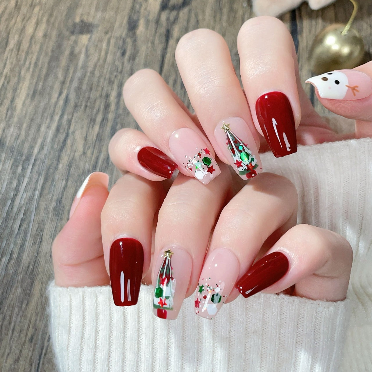 “Press-on nails featuring a charming Christmas theme with a detailed design of a deer and a Christmas tree. The deer is elegantly drawn,  adorned with ornaments and lights. The nails have a festive color palette, typically including red, green, and white, with a glossy finish, creating a holiday-inspired, whimsical, and cozy look.”